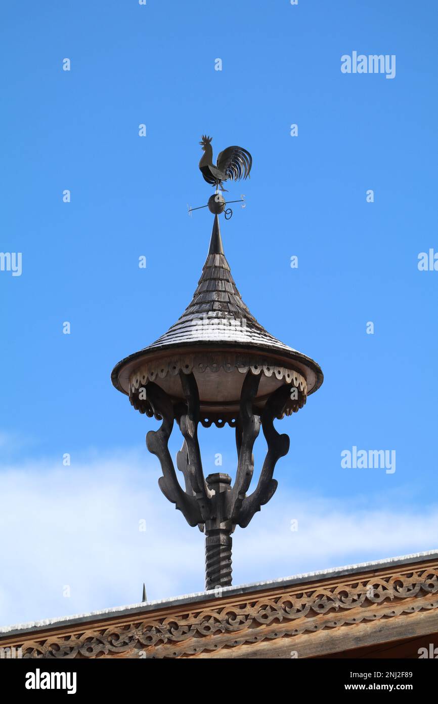 traditional sculpted wooden tirolean bell tower on the roof of a farm house with blue sky in the background Stock Photo