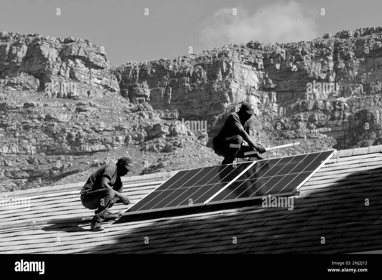 Team installing hybrid grid tied electrical installation of solar panels, inverters and backup batteries to combat loadshedding in South Africa. Stock Photo