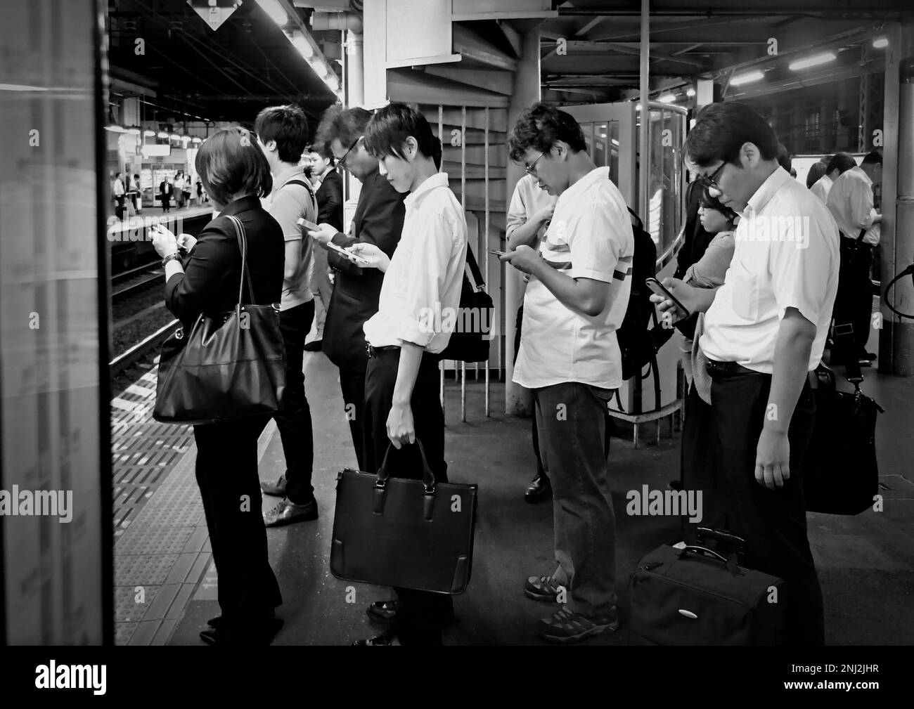 Tokyo, Japan - Sept, 2017: People waiting train on line thereat looking to their phones in Shinjuku train station, which is one of the busiest station Stock Photo