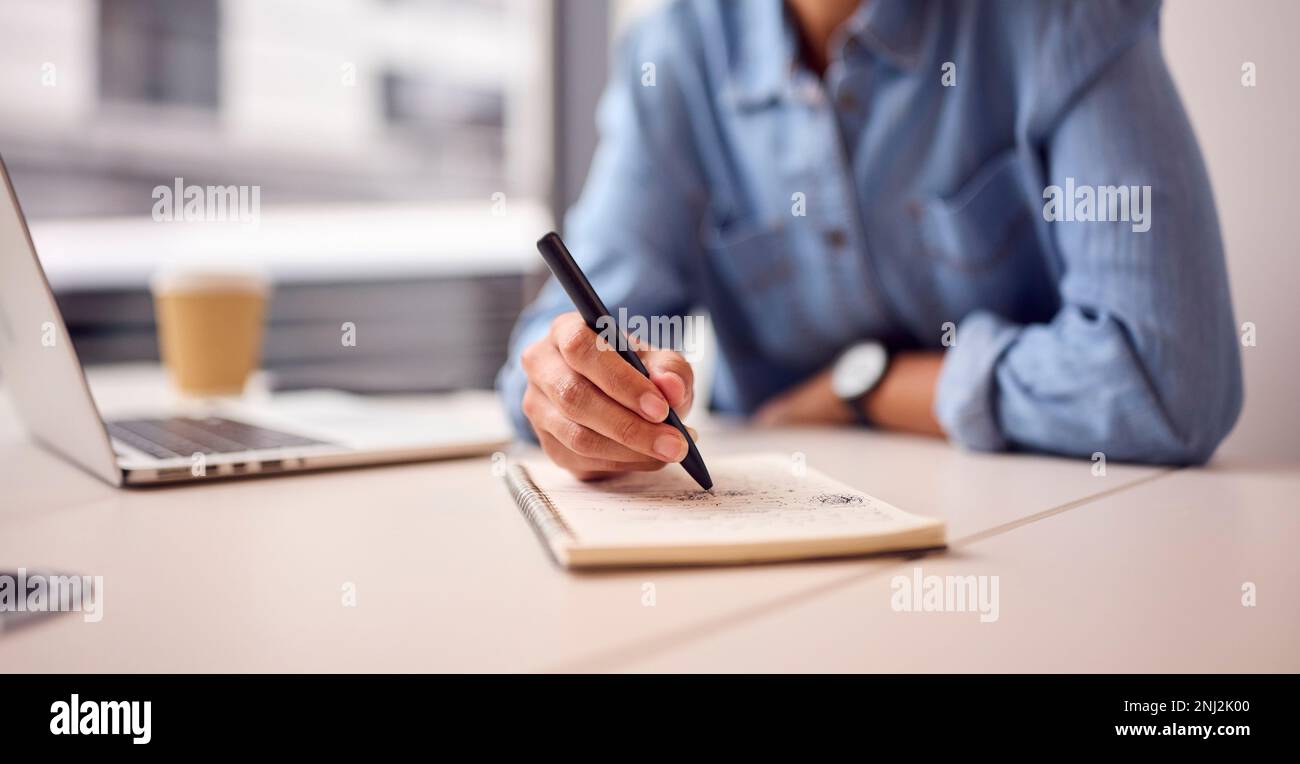 Close Up Of Businesswoman In Modern Office Working On Laptop Making Notes In Notebook Stock Photo