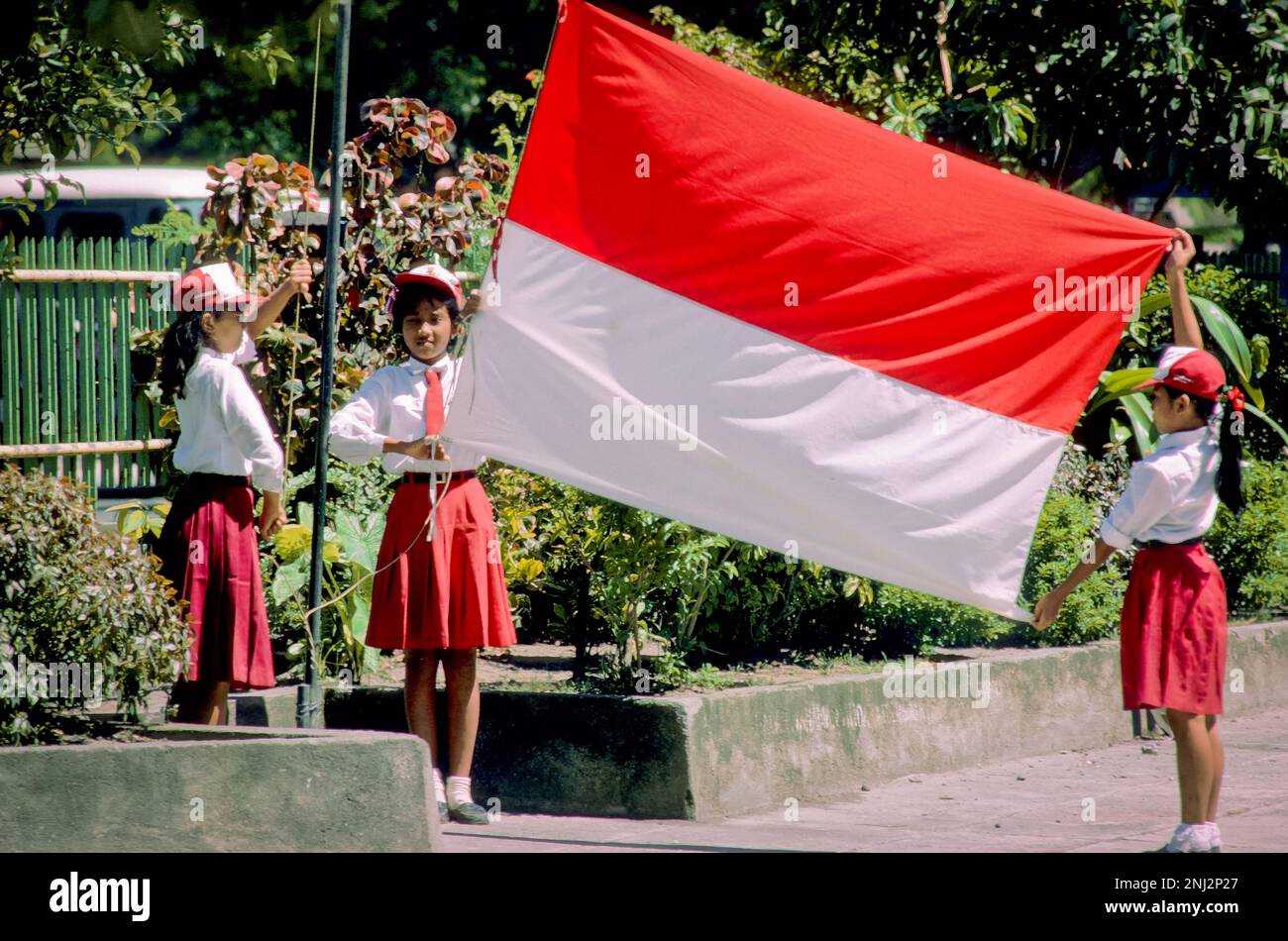 Indonesia. Schoolgirls raise the Indonesian flag. Stock Photo