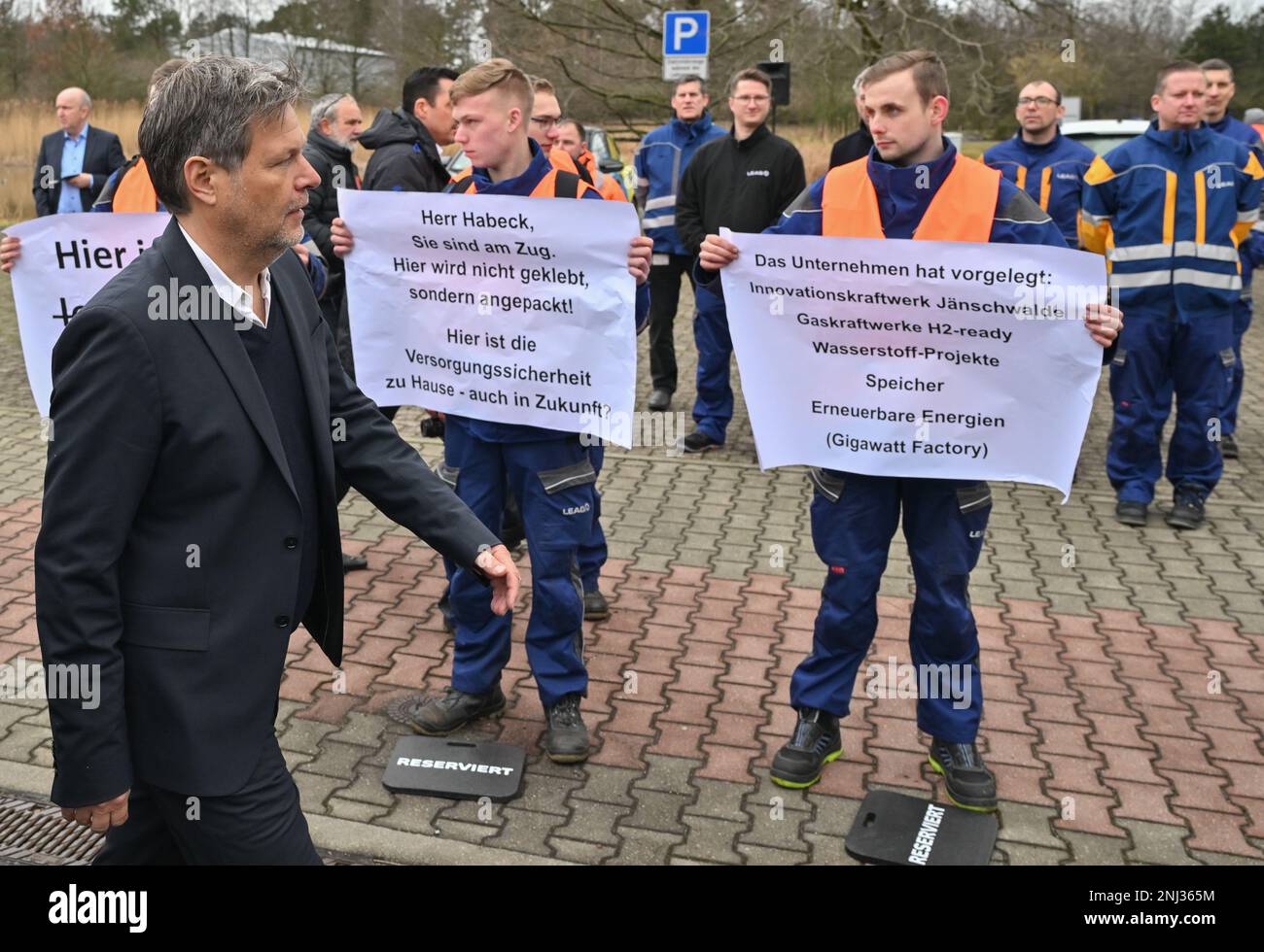22 February 2023, Brandenburg, Spremberg: Robert Habeck (l. Bündnis 90/Die Grünen), Federal Minister of Economics and Climate Protection, walks past protesting apprentices and employees during a visit to LEAG's Schwarze Pumpe lignite-fired power plant. Robert Habeck visited four sites in Lusatia, in the eastern border region between Brandenburg and Saxony, on the same day to learn about various transformation measures in the opencast mining region. An innovative hydrogen storage power plant is being built at the Schwarze Pumpe industrial park. The power plant is to supply energy generated from Stock Photo