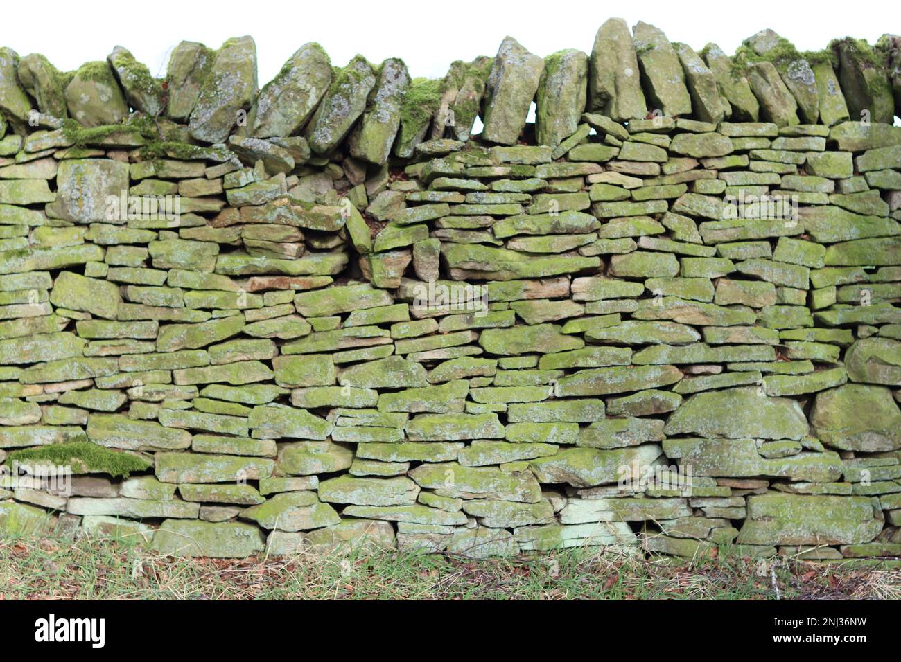 Dry stone wall tinged with green lichen Stock Photo