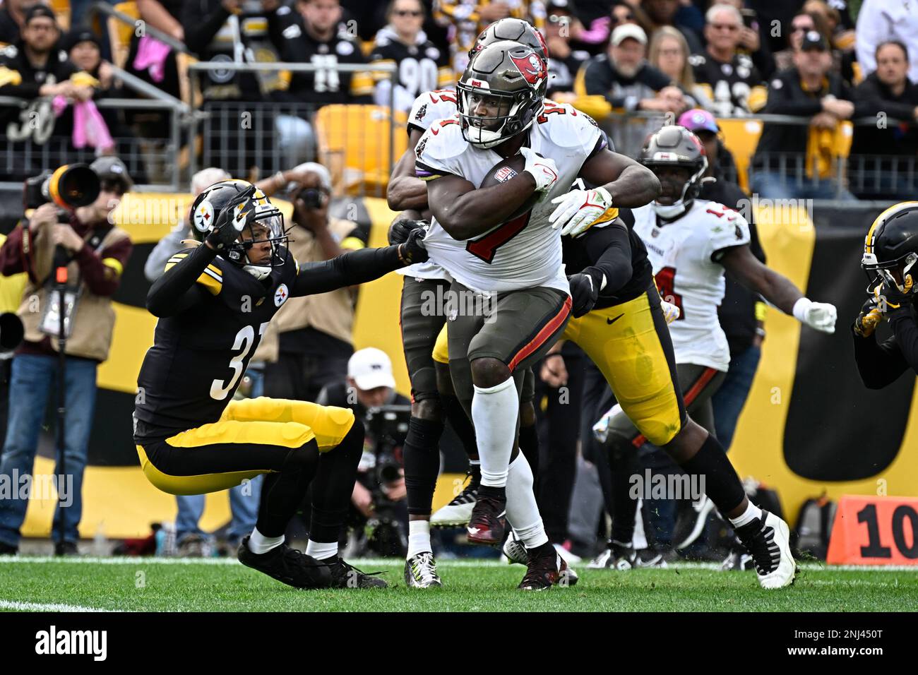 PITTSBURGH, PA - OCTOBER 16: Tampa Bay Buccaneers running back Leonard  Fournette (7) avoids a tackle by Pittsburgh Steelers cornerback Mark  Gilbert (31) before making an 11 yard touchdown in the fourth