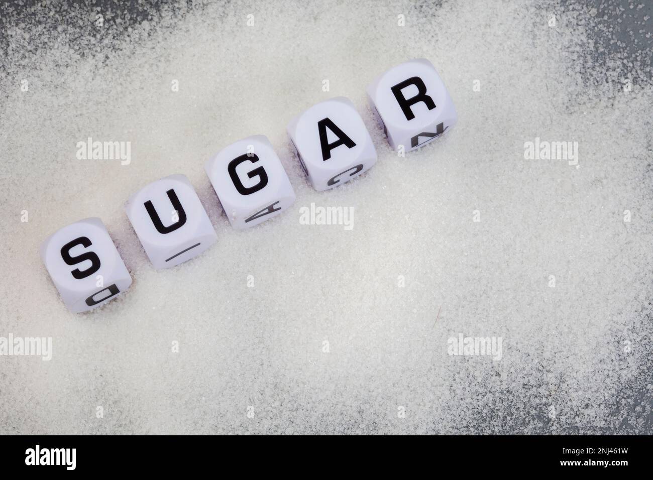 Sugar written in letter dice on white sugar granules Stock Photo
