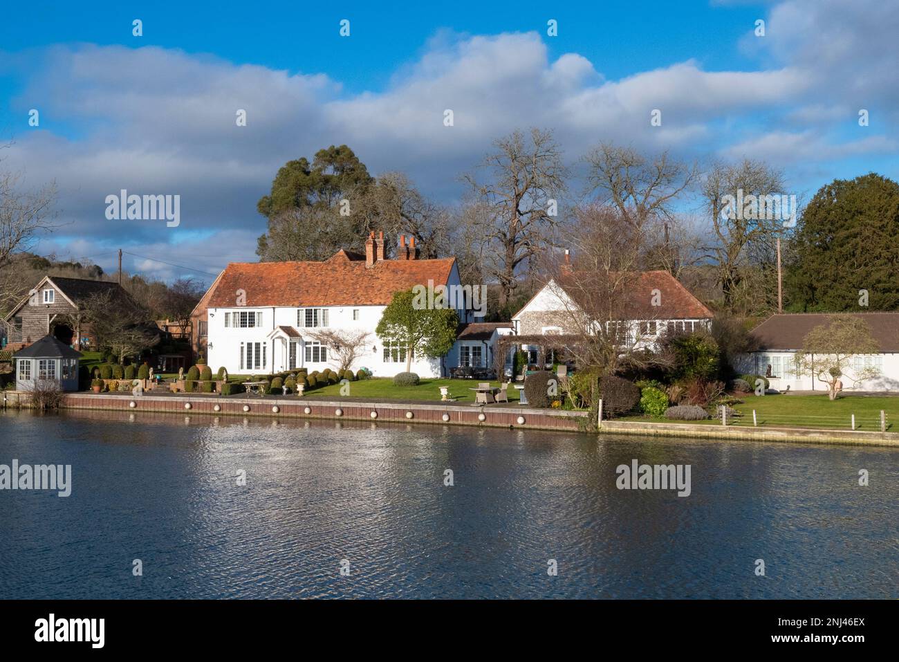 Riverside houses overlooking Hambledon weir and  lock ,upper thames on a sunny day with the Thames in flood after rain storms. nr henley-on-thames Stock Photo