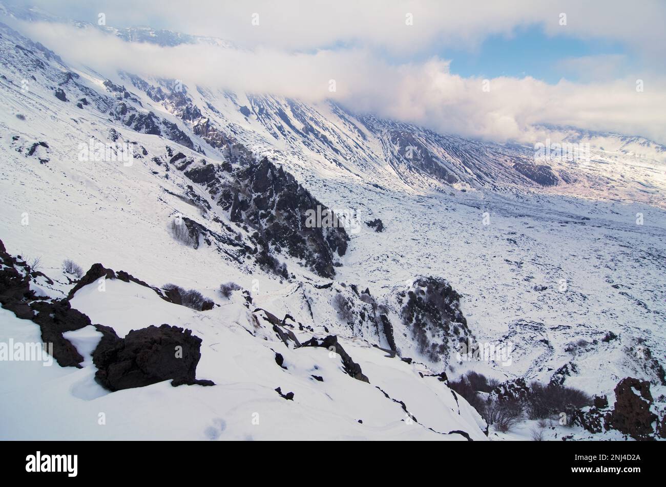 snowy landscape with volcano rocks on slope of the 'Schiena dell'Asino' at the edge with the 'Valle del Bove', Etna National Park, Sicily, Italy Stock Photo