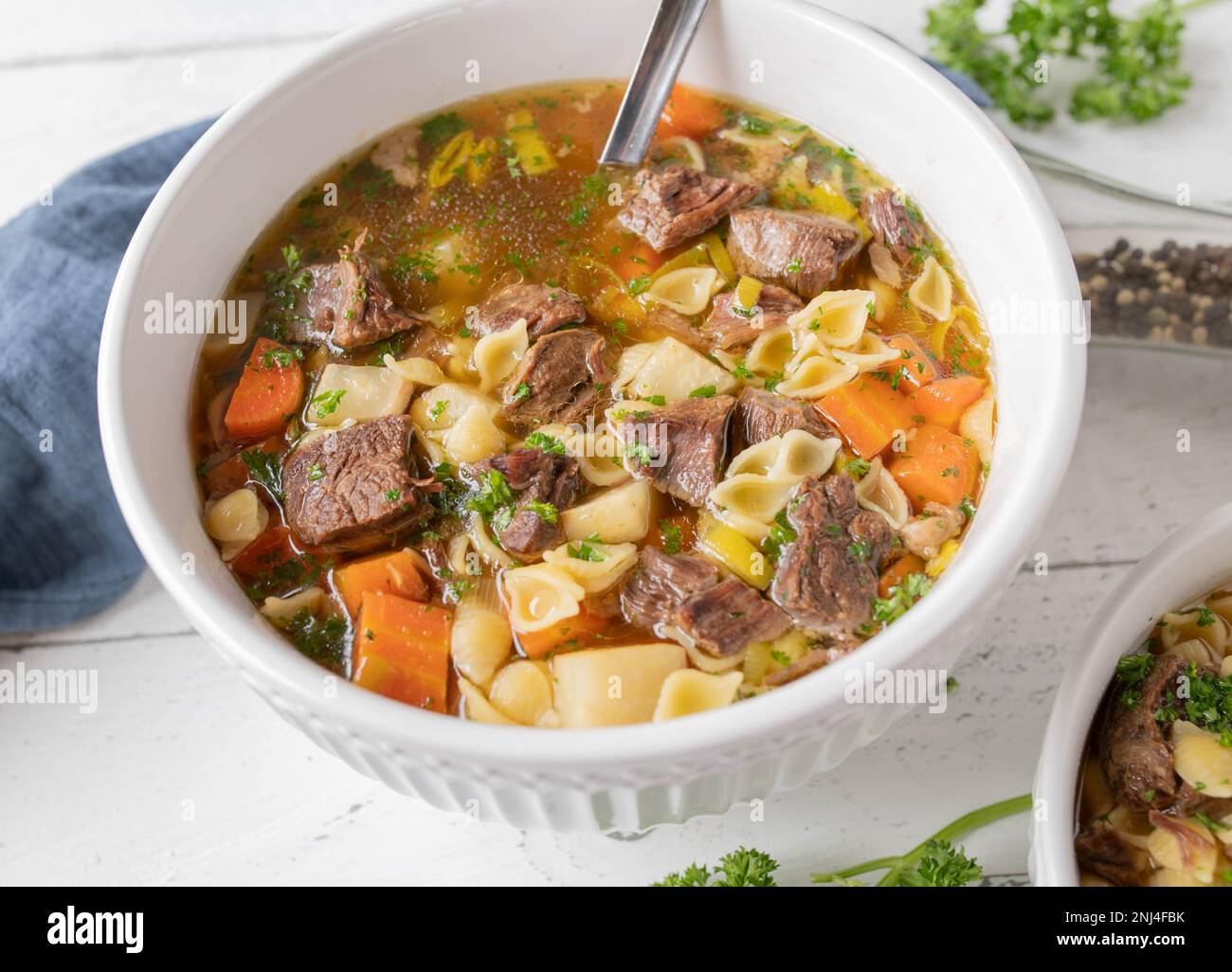 Beef noodle soup with clear broth, root vegetables and pasta in a bowl