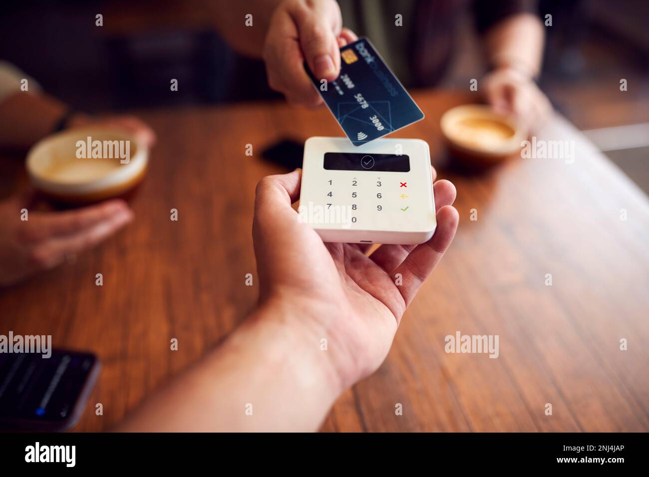 Close Up Of Customer Making Contactless Payment In Coffee Shop Using Debit Card Stock Photo