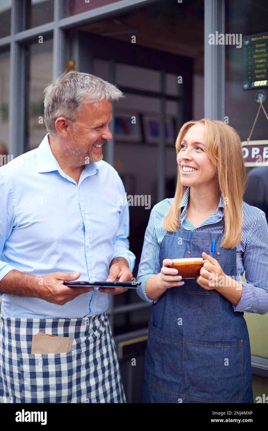 Male And Female Owners Or Staff Standing Outside Coffee Shop With ...