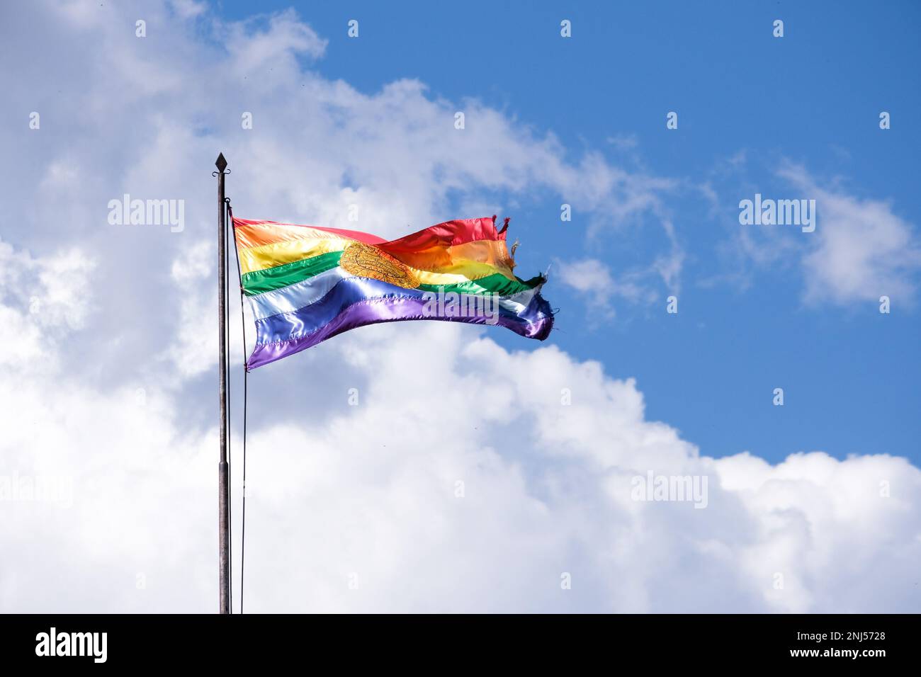 The official colorful flag of Cusco waving in the sky. It has seven horizontal stripes of color. Gay Pride flag. Stock Photo