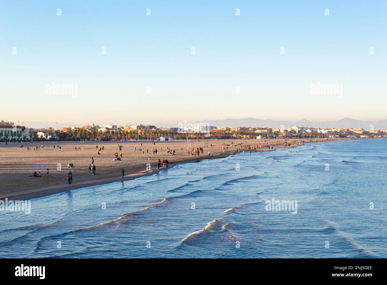 People walking along the shore of Malvarrosa beach on a quiet Sunday afternoon. Valencia - Spain Stock Photo