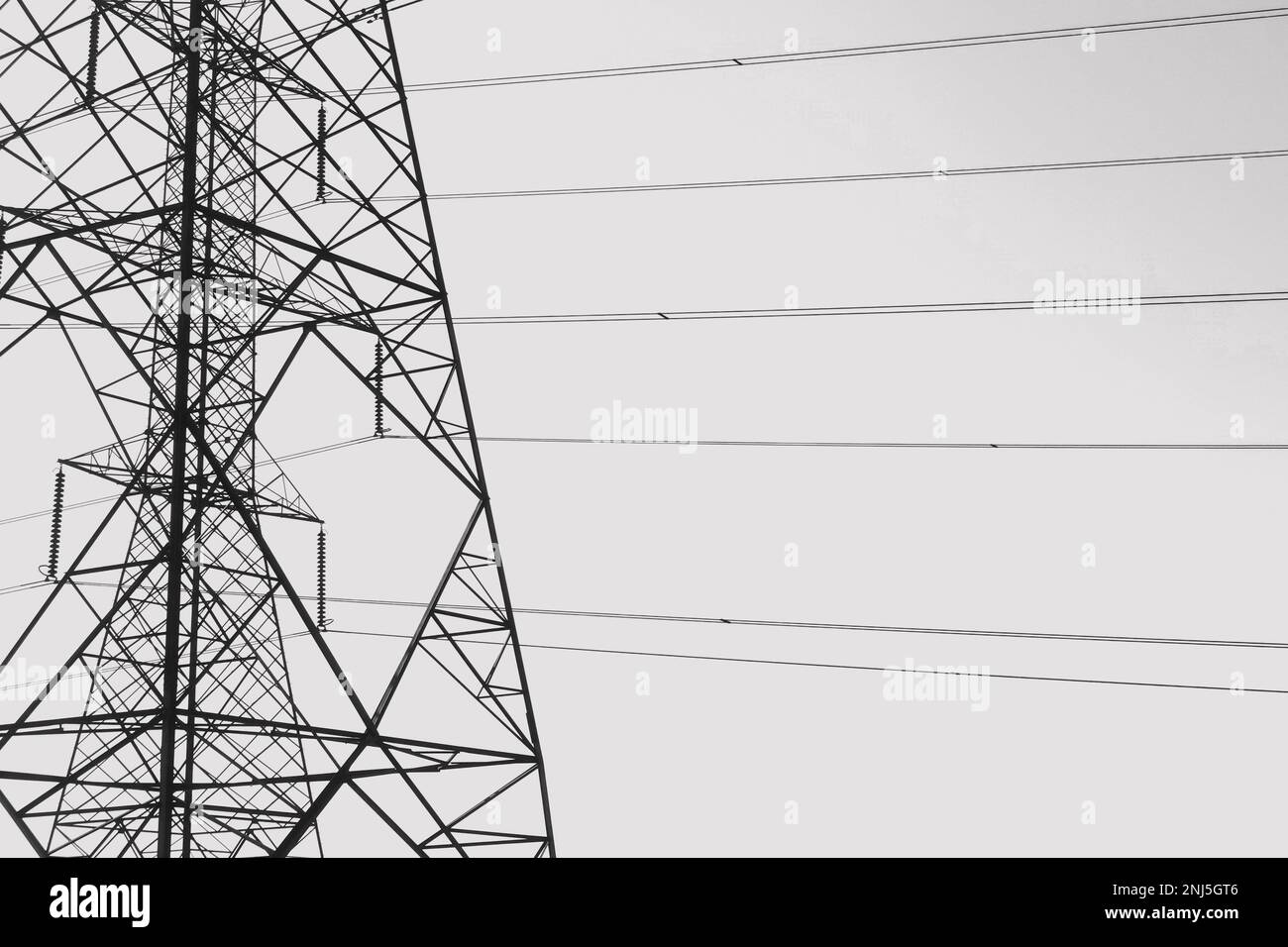 Overhead power line pylons and electrical cable wires sihouette. Black and white. Stock Photo