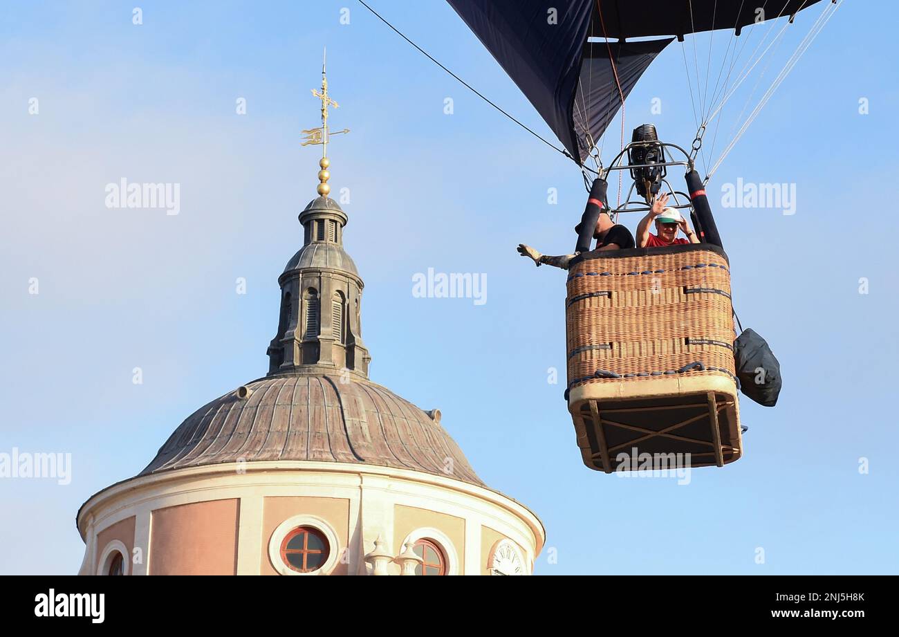 Several people ride on the barge of a zeppelin in flight over the Royal