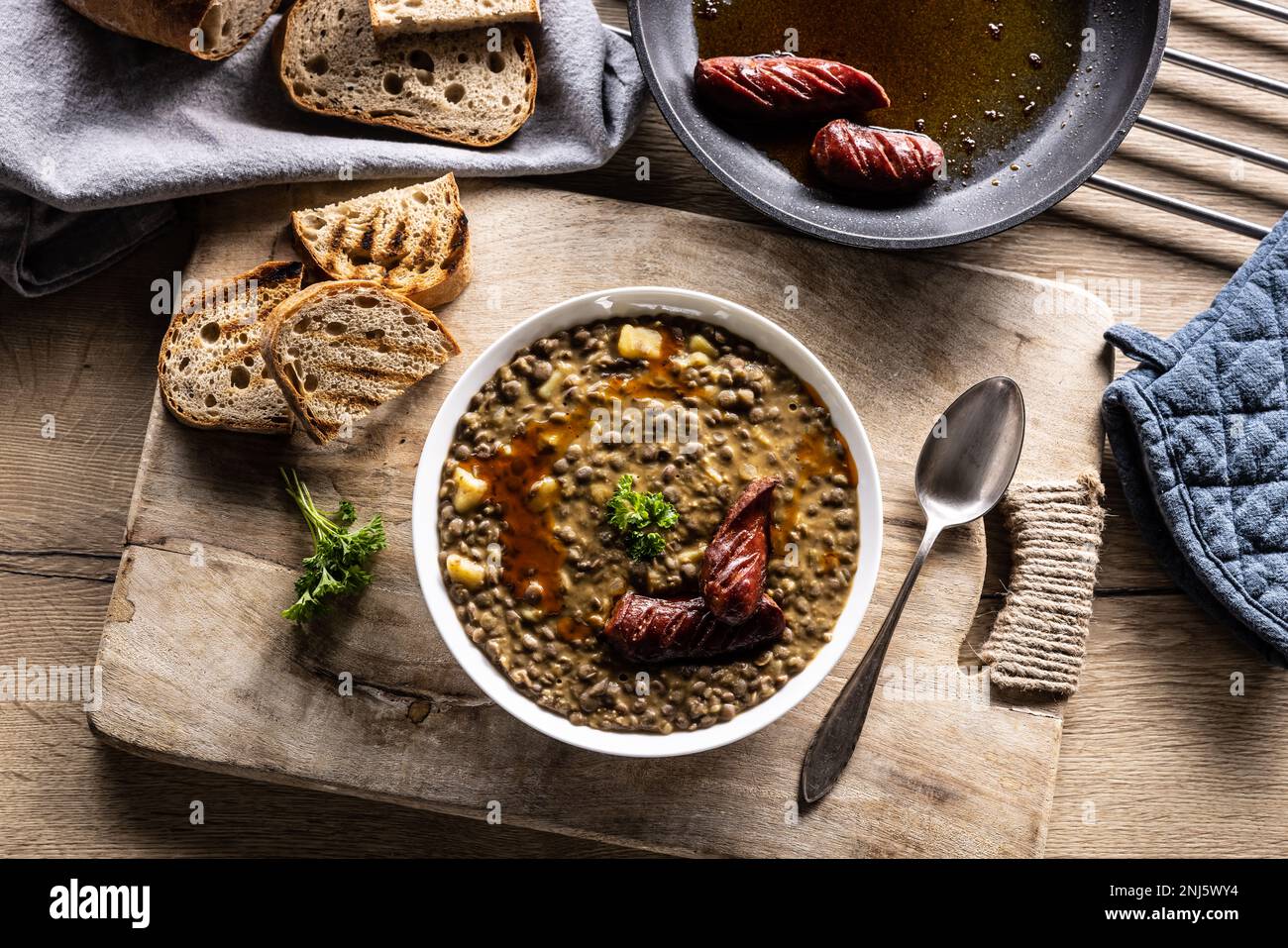 A plate full of lentil legume soup with baked sausage and fresh bread - Top of view. Stock Photo