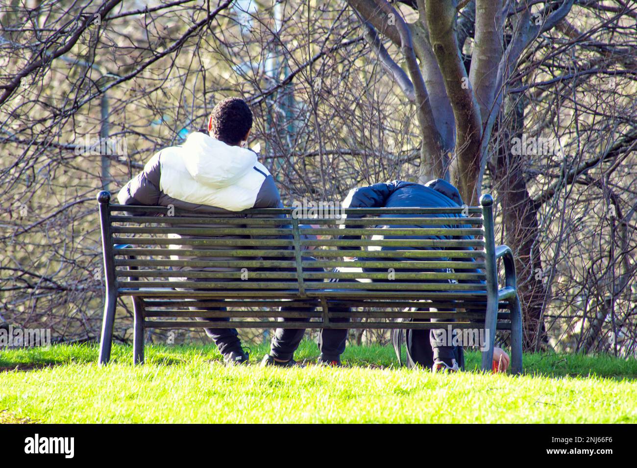 two men on a bench drinking  in a park in drumchapel Glasgow, Scotland, UK Stock Photo