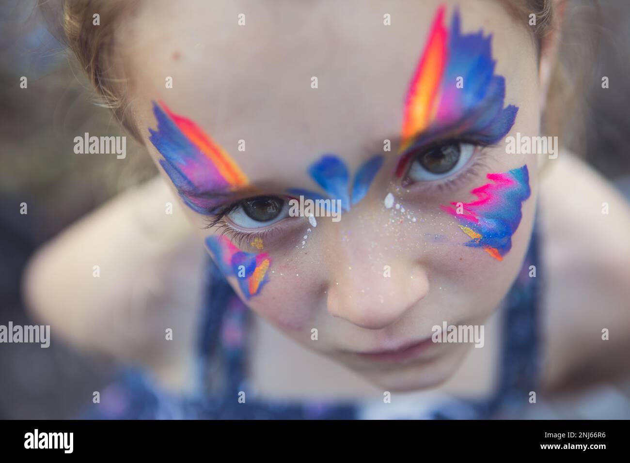 Child with vivid butterfly face painting and piercing eyes Stock Photo