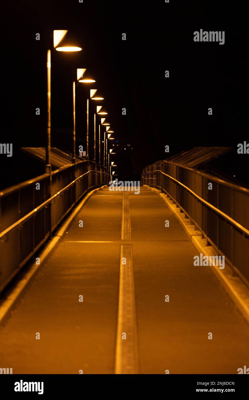 An empty illuminated walkway in the night Stock Photo - Alamy