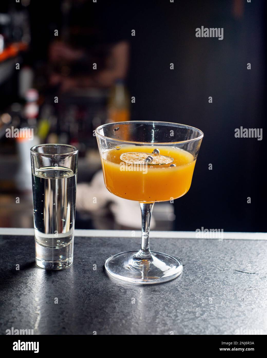 Orange cocktail and shot of vodka on the bar counter. Nightlife concept Stock Photo
