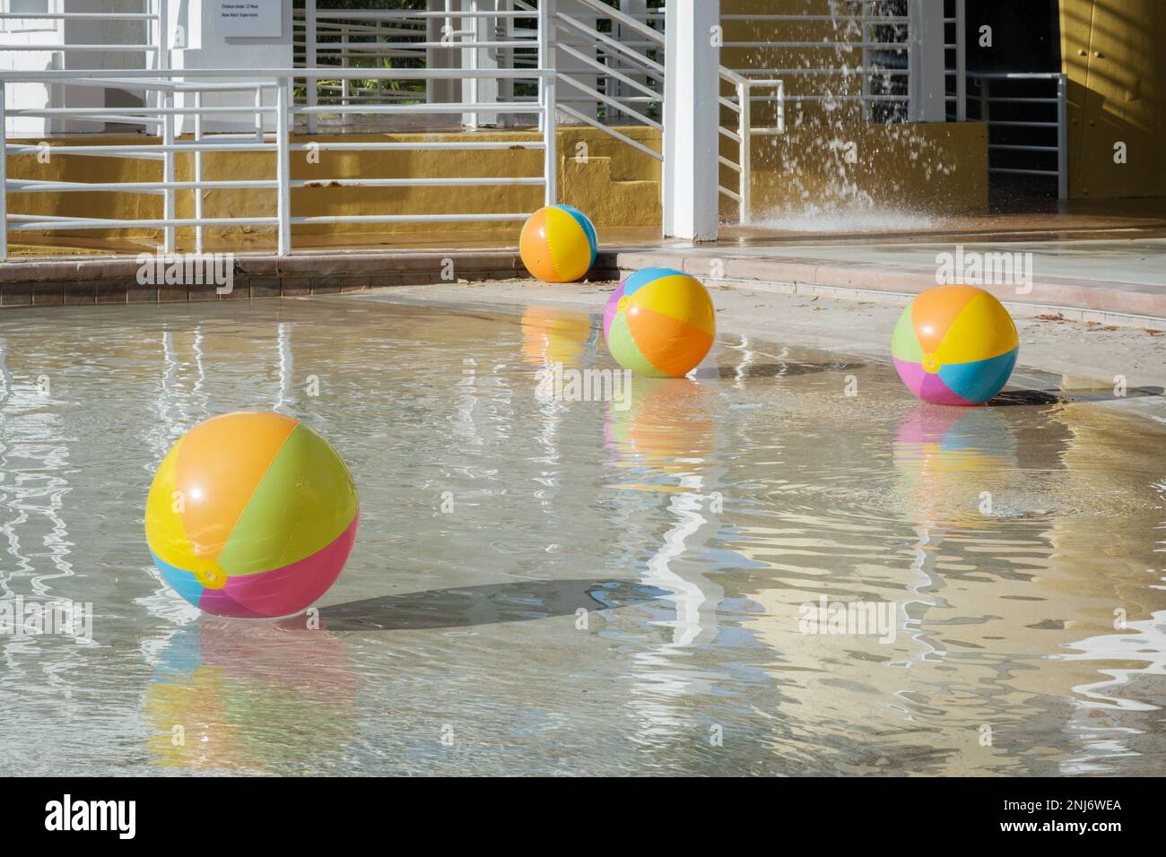 Beach balls float in the water of a resort swimming pool on a summer