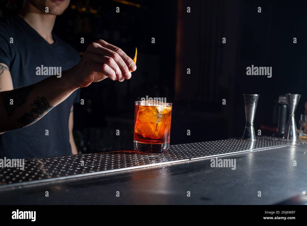 Bartender makes an orange cocktail with citrus fruits. Bar nightlife