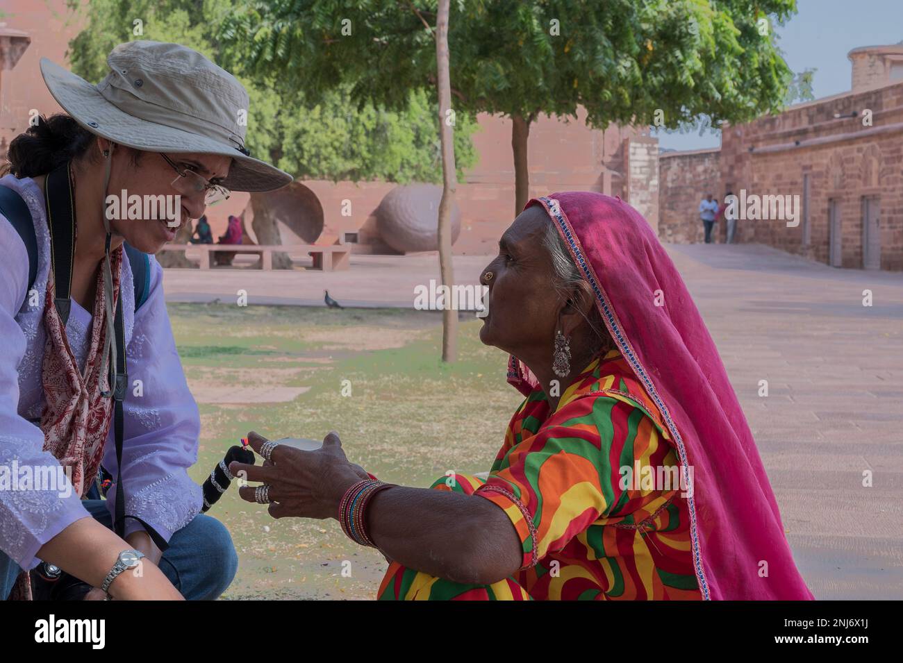 Jodhpur, Rajasthan, India - 19th October 2019 : Young Indian female tourist in modern dress speaking with old Rajasthani woman in traditional dress. Stock Photo