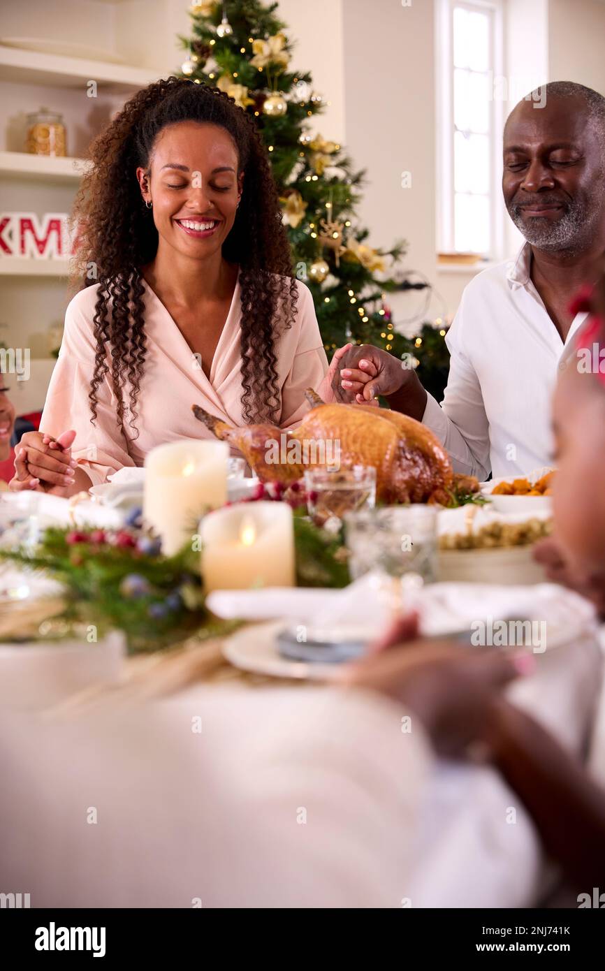 multi-generation-family-celebrating-christmas-at-home-saying-prayer
