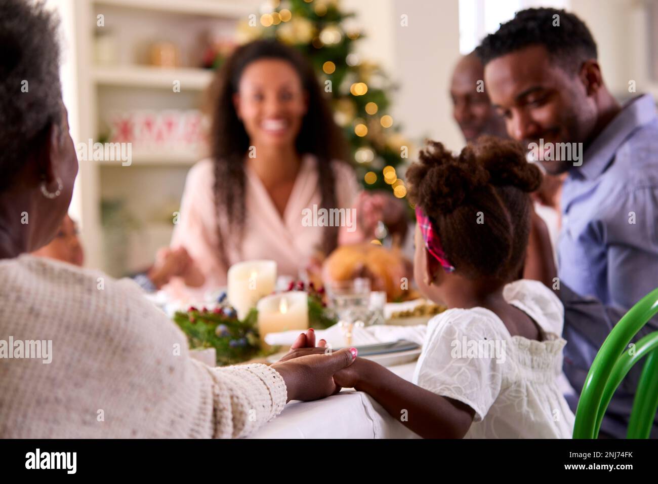 multi-generation-family-celebrating-christmas-at-home-saying-prayer