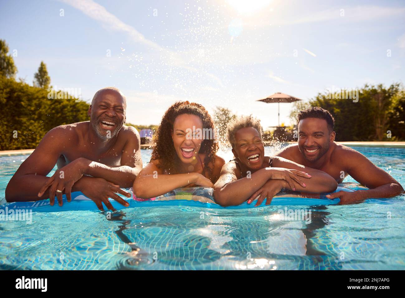 Multi-Generation Family With Adult Offspring On Summer Holiday On Inflatable In Swimming Pool Stock Photo
