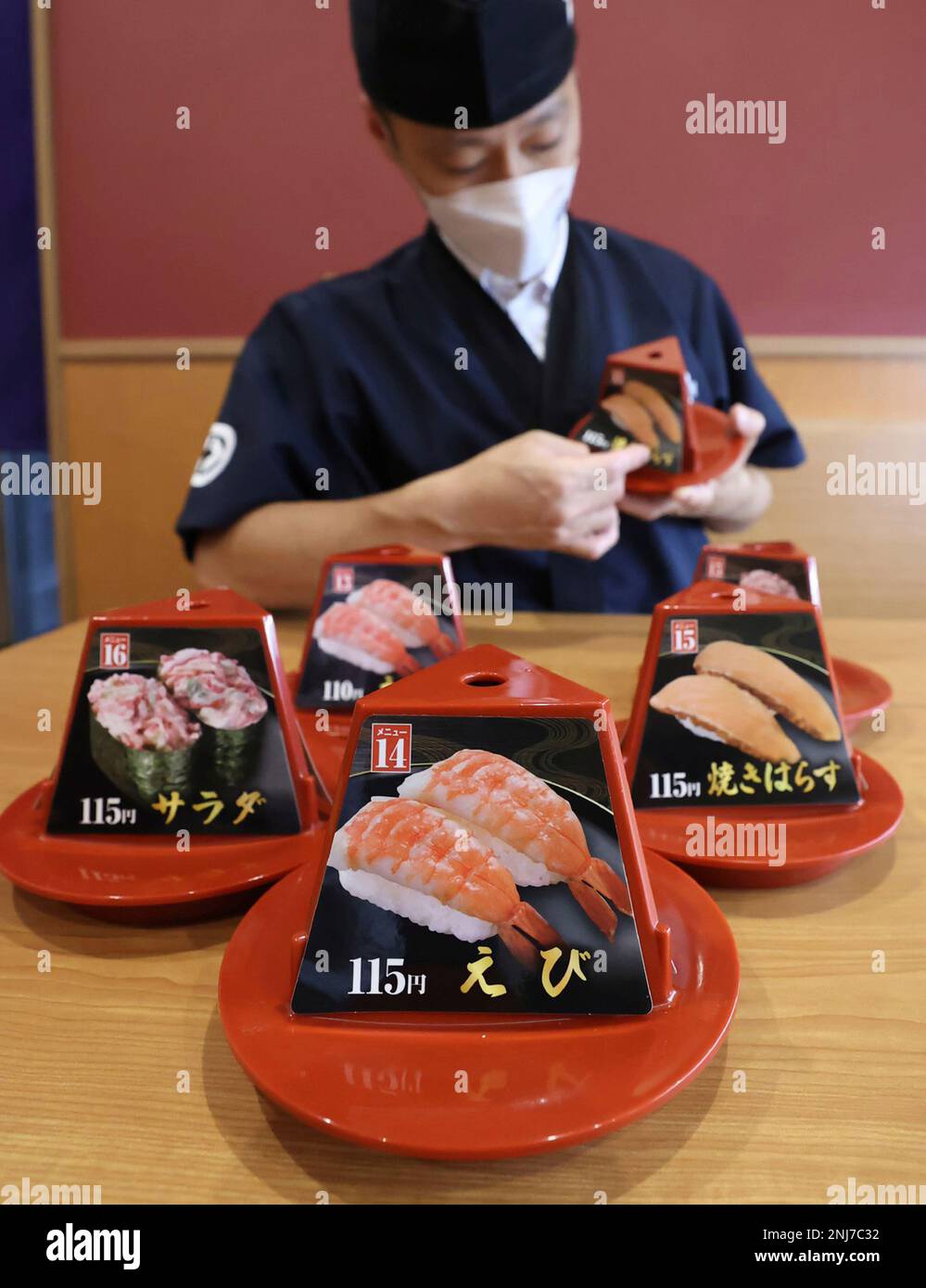 An employee changes the price tag from 110 yen to 115 yen due to