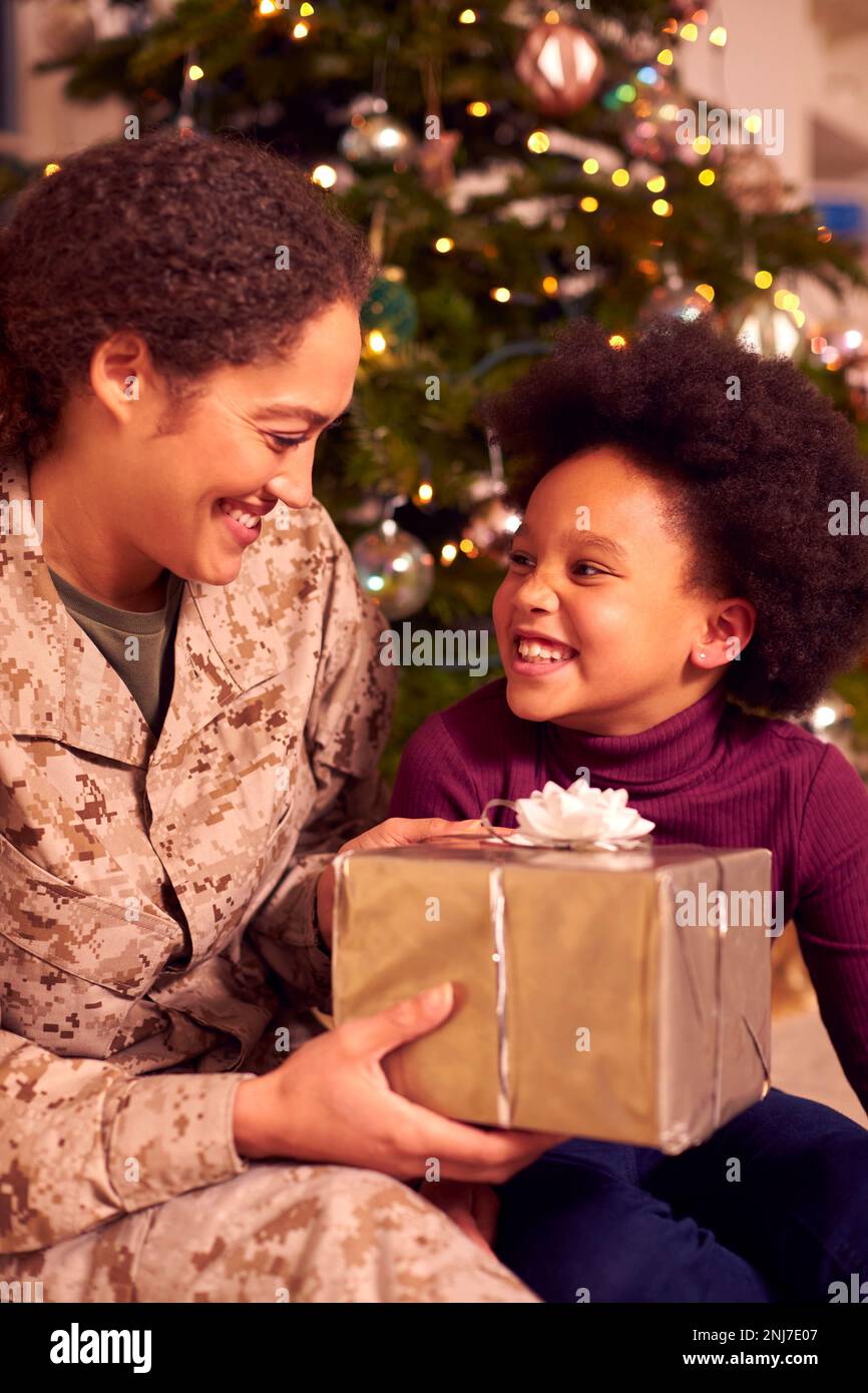 American Female Soldier In Uniform Home On Leave For Christmas Giving Daughter Present Stock Photo