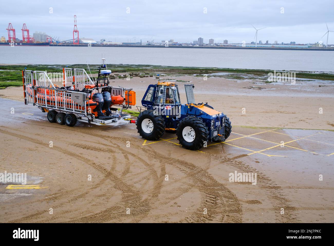 New Brighton life boat crew recovering the boat back up the beach with tractor towing the rib on a trailer after completing a rescue out to sea Stock Photo
