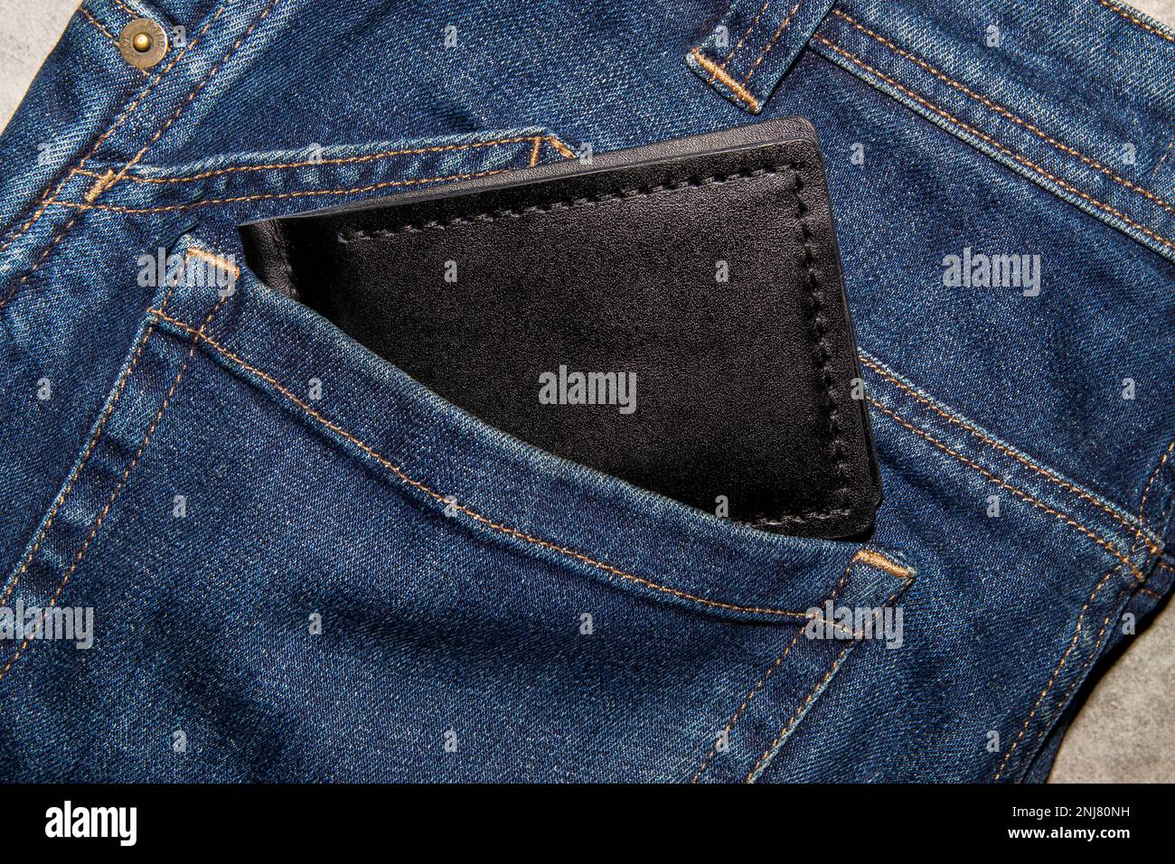 Black handmade leather wallet on blue jeans. Male background. View from above. Stock Photo