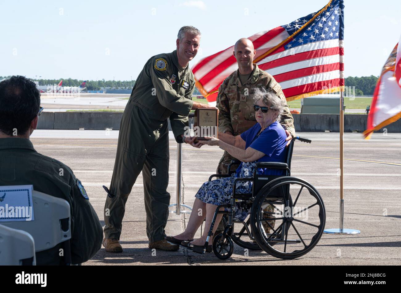 Glenda Bryant, wife of retired Lt. Col. Melvin “Mel” Bryant, left, passes off a bottle of scotch to U.S. Air Force Col. George Watkins, 325th Fighter Wing commander, right, beside her grandson, back left, during a dedication ceremony at Eglin Air Force Base, Florida, August 6, 2022. The 101-year-old bottle was donated to the 325th Fighter Wing by Glenda as a keepsake from World War II, honoring the 2nd Pursuit Squadron. Stock Photo