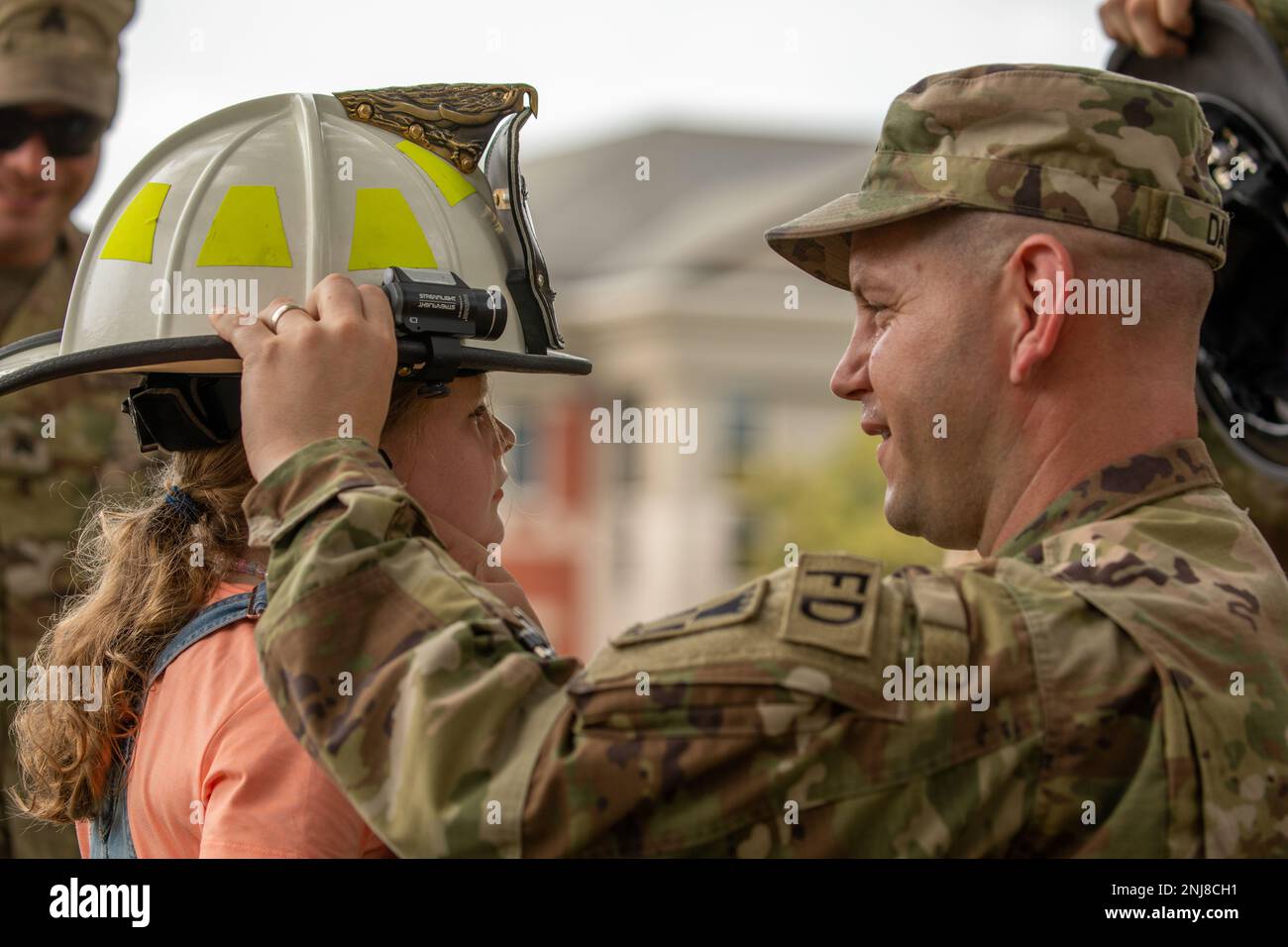 Birdie Amerson, 6, of Des Moines, tries on a firefighter helmet with the help of Staff Sgt. Alek Davis, 516th Engineer Detachment, of Cedar Falls during a U.S. Army Reserve open house at Fort Des Moines, Aug. 6, 2022. The based is home to the 103rd Sustainment Command (Expeditionary) and more than 20 other units from the Army Reserve. Stock Photo