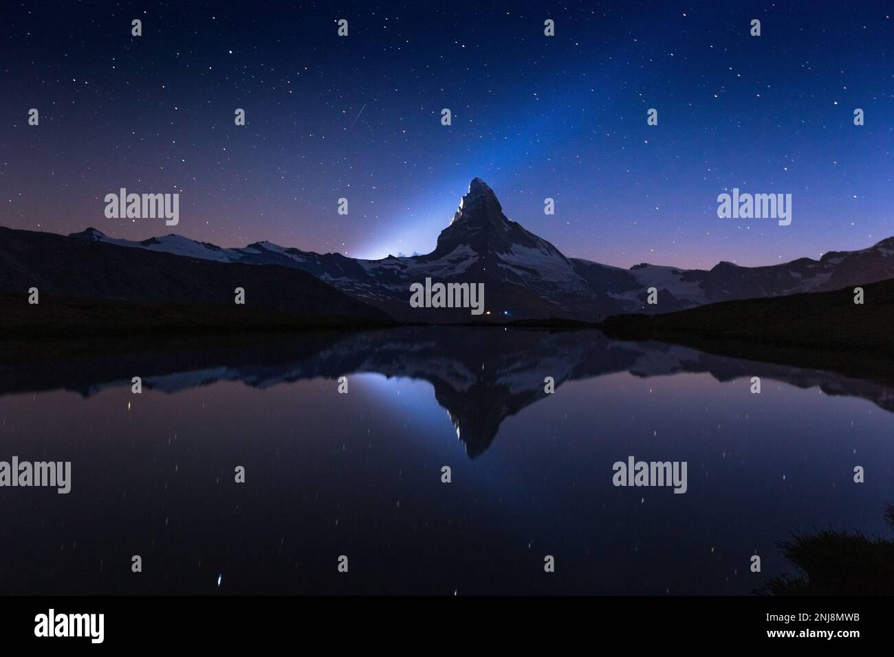 The celebration of 150 years from first ascent of the Matterhorn (Cervino). Reflection on Lake Stellisee. Beam of light. Night landscape. Swiss Alps. Stock Photo