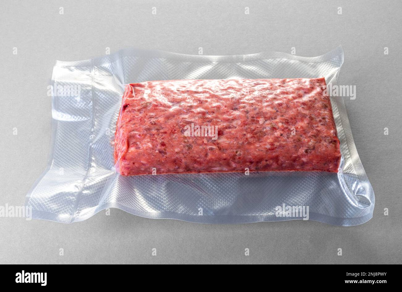 Raw minced meat roll in vacuum pack for sous vide cooking on gray