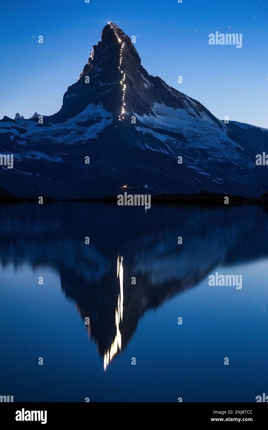 The celebration of 150 years from first ascent of the Matterhorn (Cervino). Reflection on Lake Stellisee. Night landscape. Swiss Alps. Europe. Stock Photo