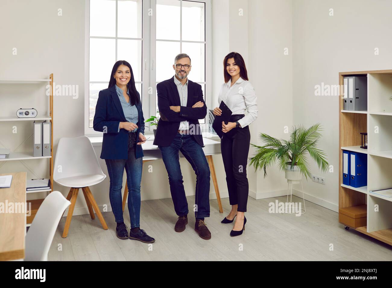 Successful business team standing together looking at camera and ...