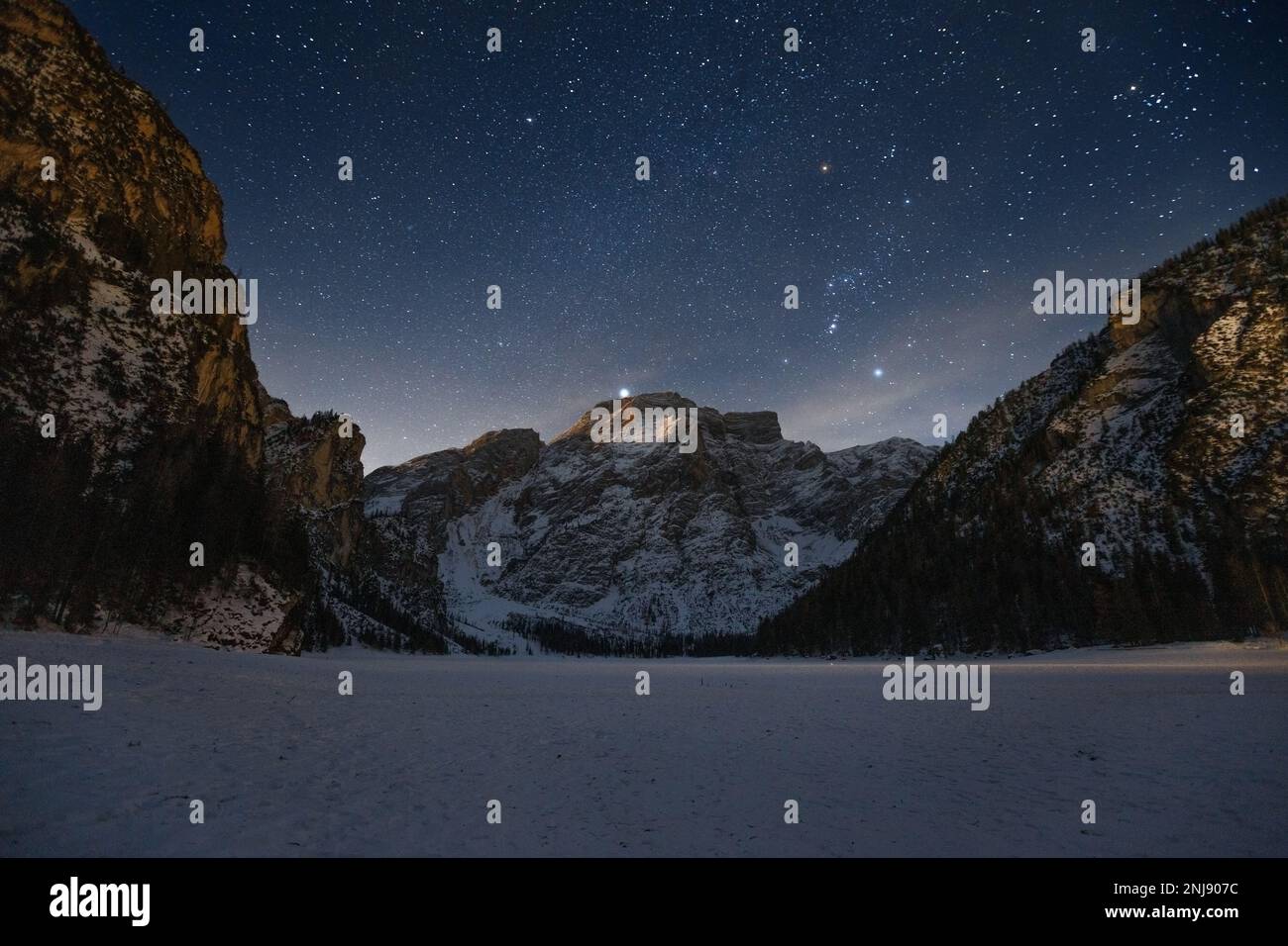 Lake Braies (Lago di Braies), night landscape, starry sky and moonrise light. View on Seekofel (Croda del Becco) mountain. Winter, South Tyrol, Italy. Stock Photo