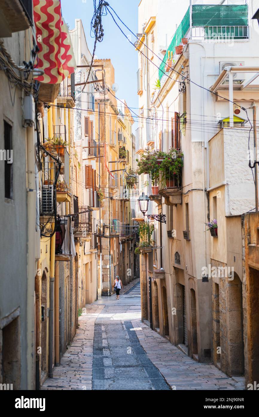 TARRAGONA, SPAIN - AUGUST 6, 2022: Narrow street in the old town of Tarragona, a tourist port city by the Mediterranean Sea in the northeast of Spain. Stock Photo