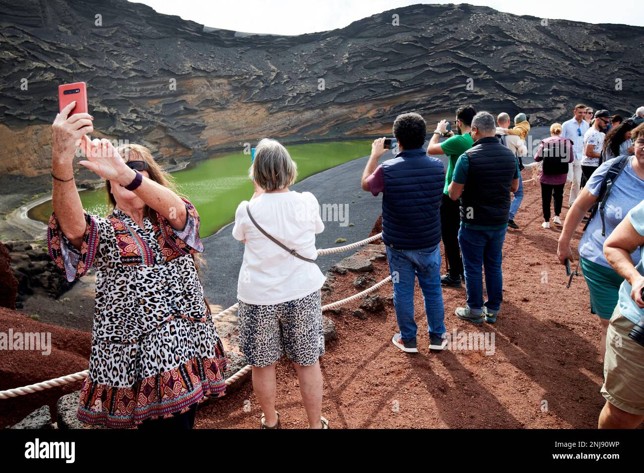 tourists take photos at the viewing spot above the green lake at el golfo Lanzarote, Canary Islands, Spain Stock Photo