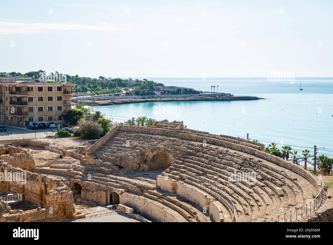 Wide-angle view of the ruins of the Roman amphitheater in Tarragona, built in the 2nd century AD, with the Mediterranean Sea in the background. Stock Photo