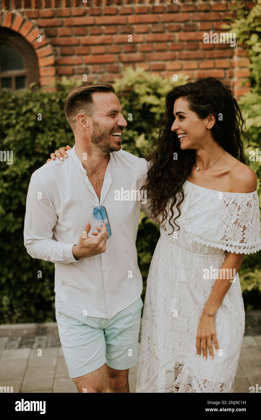 Happy young couple is enjoying the beautiful surroundings of a garden, basking in the sun and each other's company Stock Photo