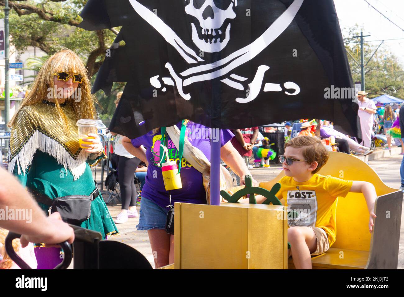 Mother and son with pirate flag and cardboard 'ship' strolling the street before parades begin on Mardi Gras day in New Orleans. Stock Photo