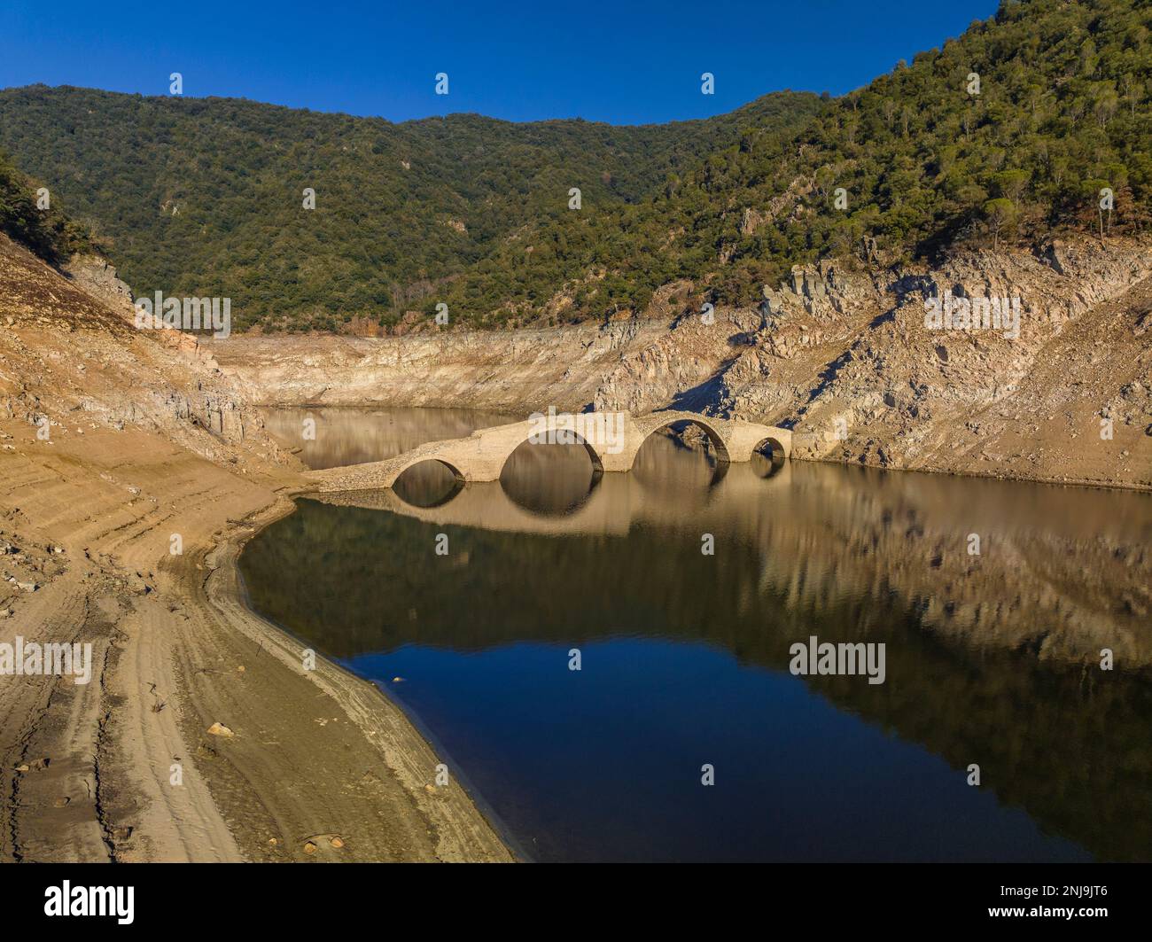 Aerial view of the medieval bridge of Querós, in the Susqueda reservoir, visible during a drought with the reservoir level at 36% (Catalonia, Spain) Stock Photo