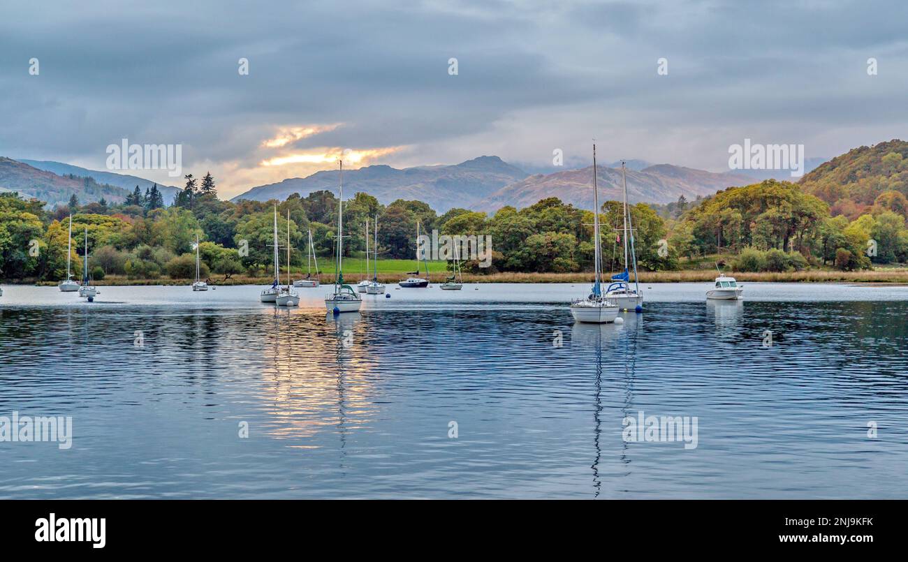 Yachts moored on Lake Windemere at sunset with mountain peaks in the background Stock Photo
