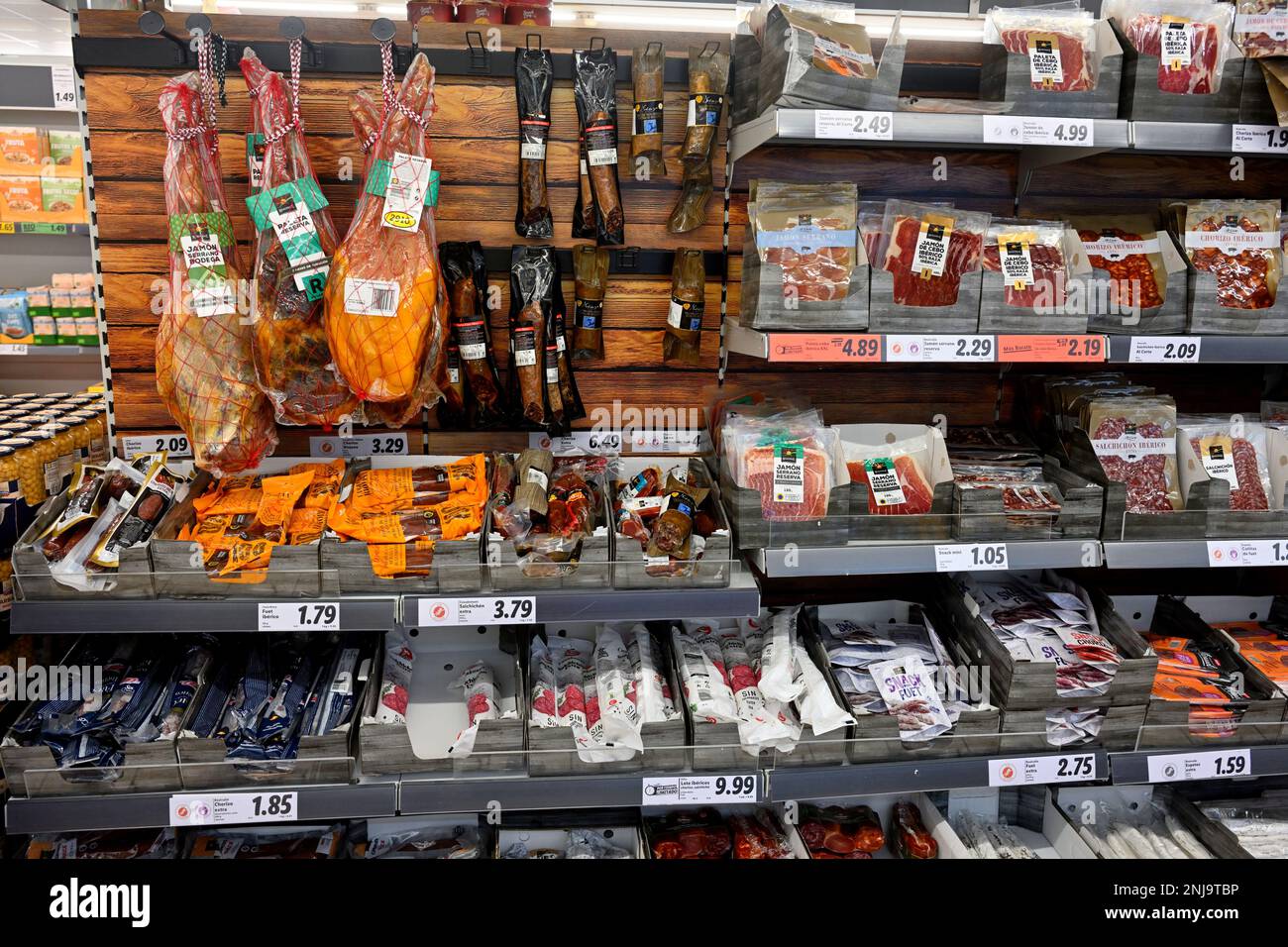 Supermarket shelves with packets of preserved cured meats, salami, chorizo, bacon, hams, sausages Stock Photo
