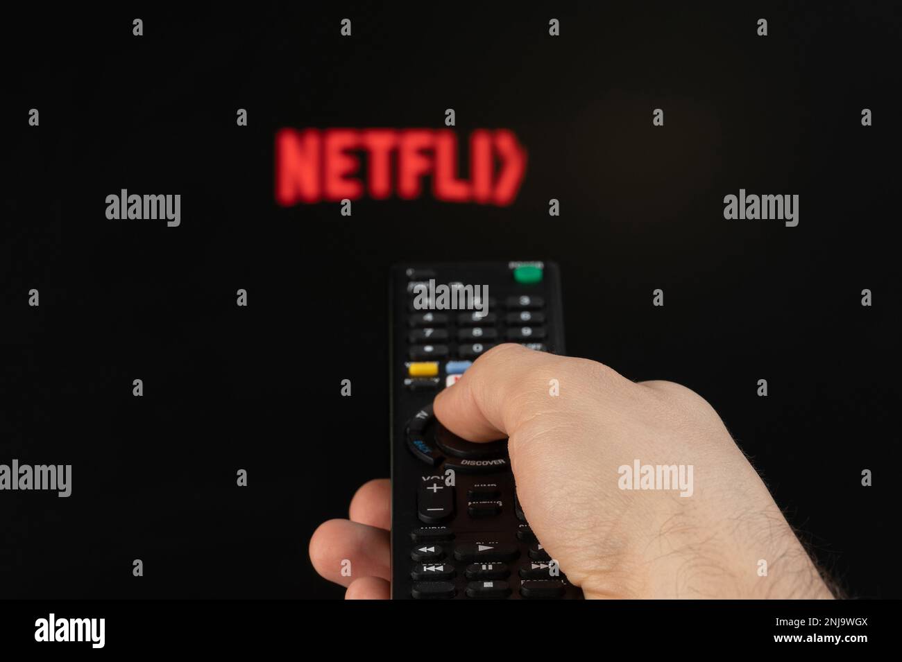 New york, USA - February 21, 2023: Play netflix streaming platform on tv with remote control in hand Stock Photo