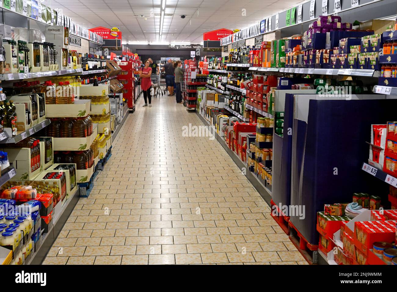 Inside supermarket with aisle full of mixed food items and customers Stock Photo